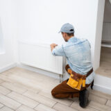 close up male plumber fixing thermostat using wrench home