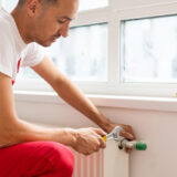 close up mature mechanic hands repairing heating system