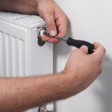 plumber installing new steel hot water central heating radiator